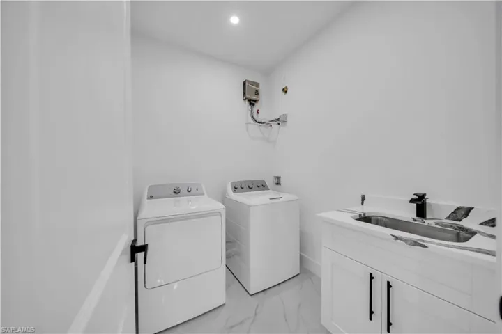 Laundry room with light marble finish flooring, cabinet space, independent washer and dryer, and recessed lighting