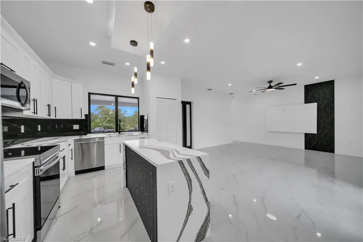 Kitchen featuring pendant lighting, light marble finish flooring, light stone countertops, a center island, and recessed lighting