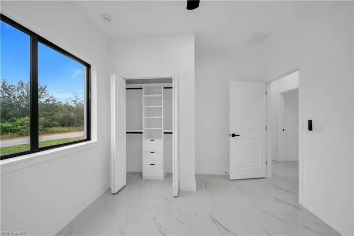 Unfurnished bedroom featuring light marble finish flooring, a closet, and a ceiling fan