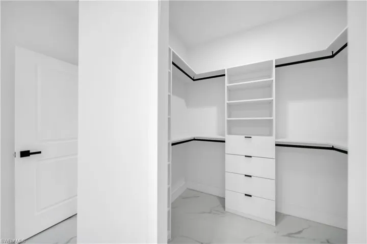 Spacious closet featuring light marble finish floors