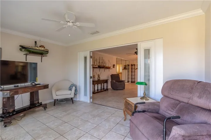 Living room featuring crown molding, visible vents, ceiling fan, and baseboards