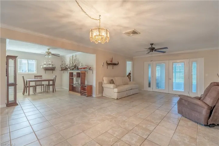 Living room with visible vents, ceiling fan with notable chandelier, french doors, and crown molding
