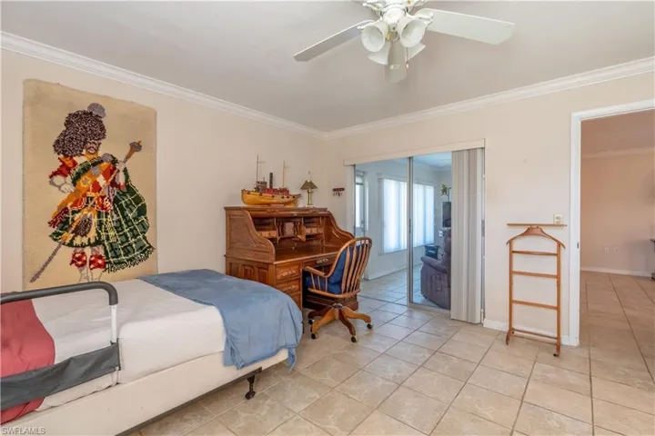 Bedroom with crown molding, a ceiling fan, light tile patterned floors, and access to exterior