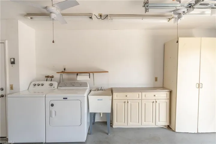 Washroom featuring a sink, cabinet space, washing machine and clothes dryer, and ceiling fan