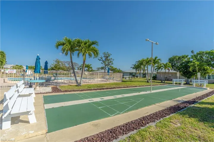 View of property's community featuring fence, a pool, and shuffleboard