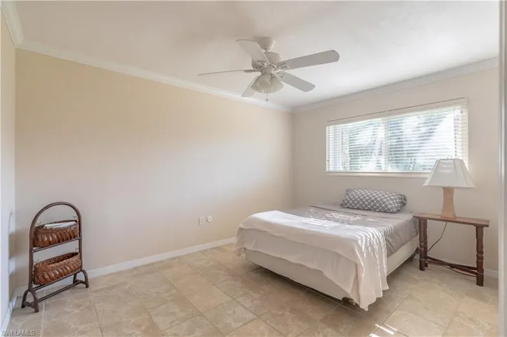 Bedroom featuring a ceiling fan, ornamental molding, and baseboards