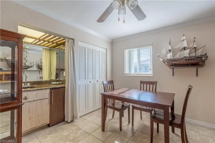 Dining room with crown molding, a ceiling fan, and light tile patterned flooring