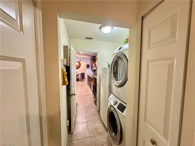 Laundry area with stacked washer / dryer and light tile patterned floors