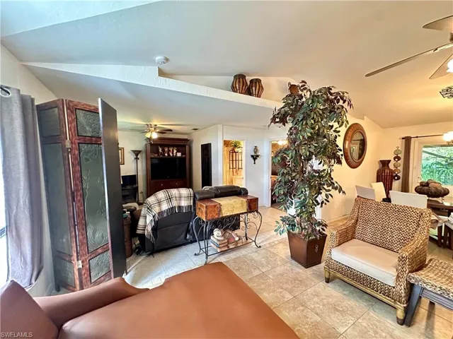 Living room featuring lofted ceiling, light tile patterned floors, and ceiling fan
