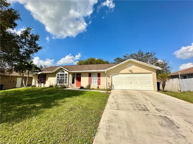 Ranch-style house featuring a garage and a front lawn
