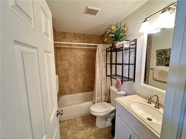 Full bathroom with tile patterned flooring, vanity, toilet, and shower / tub combo