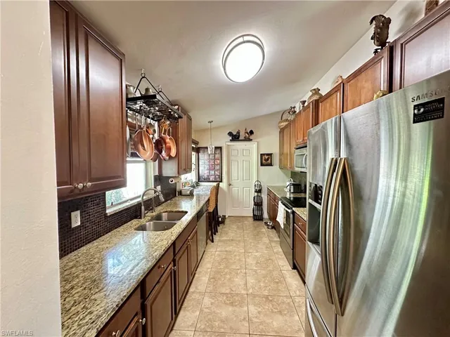 Kitchen featuring stainless steel appliances, lofted ceiling, decorative backsplash, sink, and pendant lighting