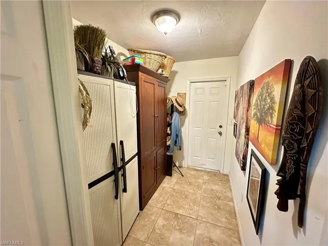 Laundry room with a textured ceiling and light tile patterned floors