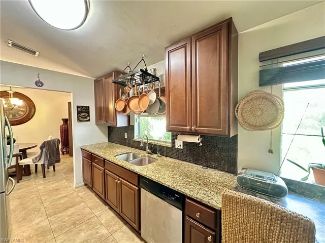 Kitchen featuring tasteful backsplash, light stone counters, stainless steel appliances, light tile patterned floors, and sink