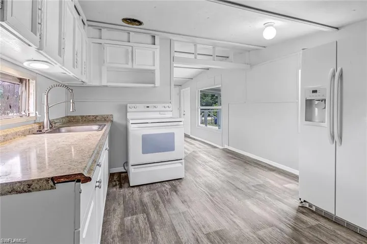 Kitchen with white cabinets, white appliances, sink, and a wealth of natural light