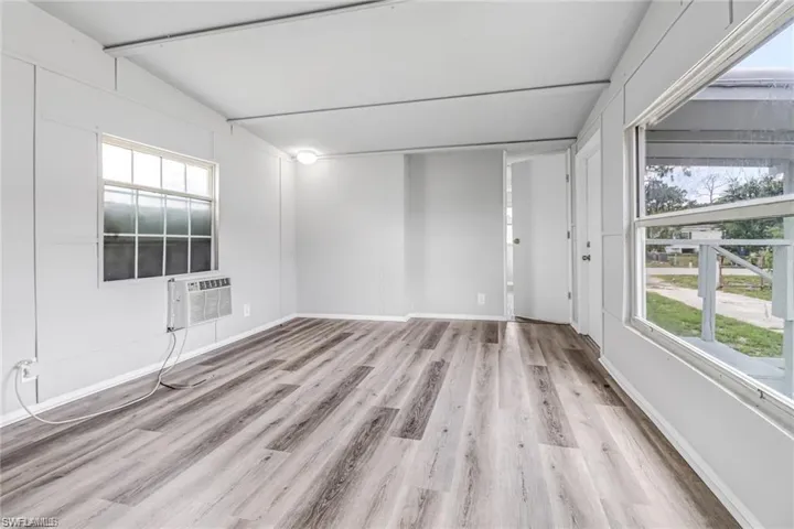 Empty room with a wealth of natural light, light wood-type flooring, and lofted ceiling