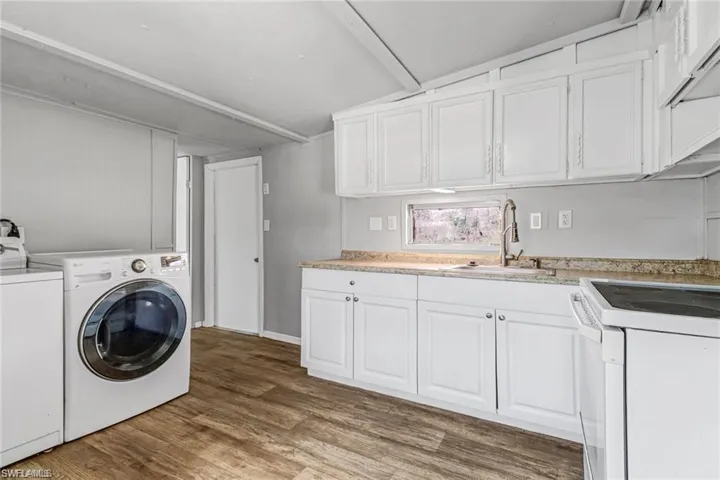 Laundry area with hardwood / wood-style floors, washing machine and dryer, and sink
