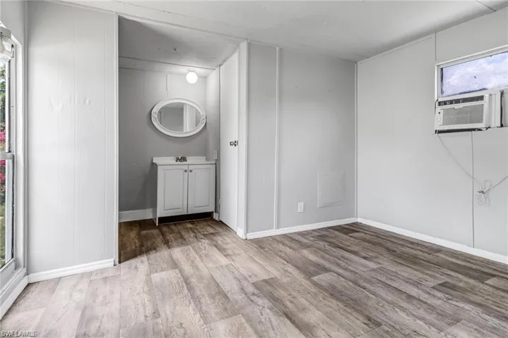 Unfurnished bedroom with light wood-type flooring, multiple windows, and cooling unit