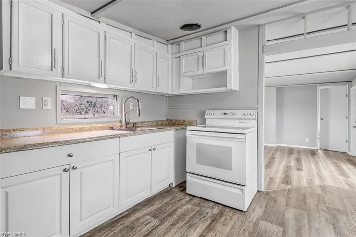 Kitchen featuring hardwood / wood-style floors, white cabinetry, sink, and white electric range