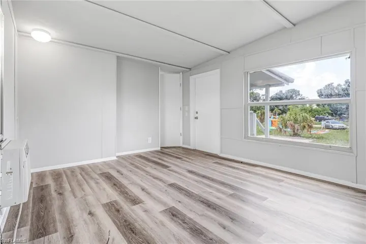 Empty room with vaulted ceiling and light hardwood / wood-style flooring