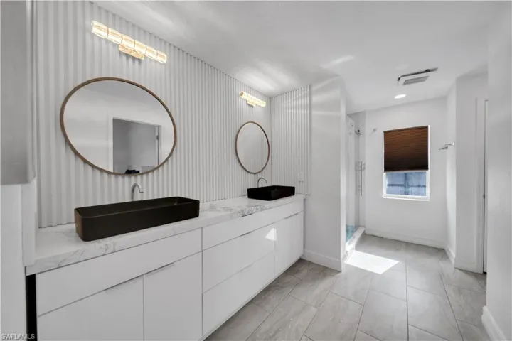Bathroom featuring double vanity, a shower stall, and recessed lighting