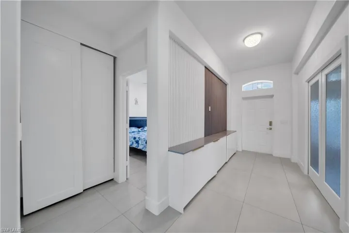 Hall with light tile patterned flooring and baseboards