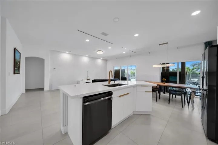 Kitchen with white cabinetry, modern cabinets, dishwasher, open floor plan, and a kitchen island with sink