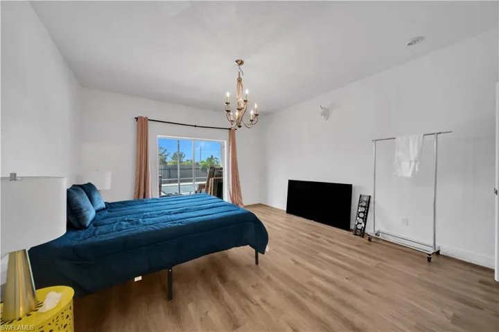 Bedroom with access to outside, light wood-style flooring, and a chandelier