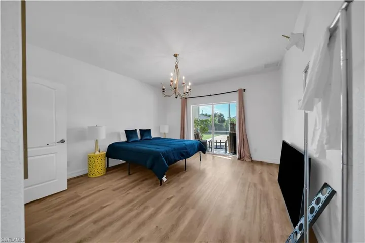 Bedroom featuring light wood-type flooring, access to exterior, and a chandelier