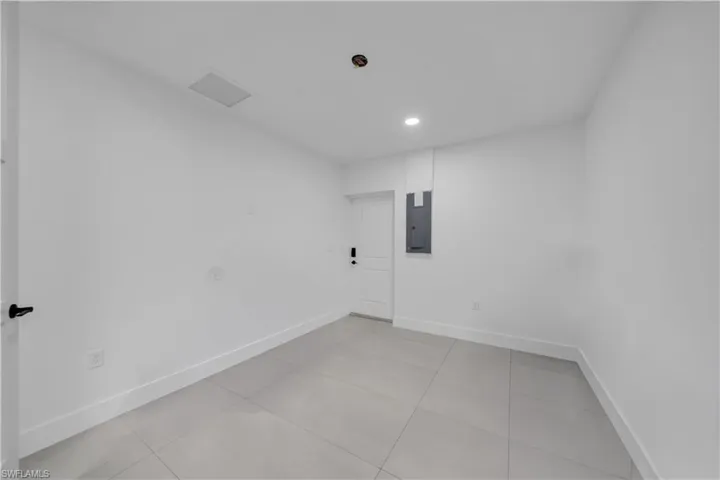 Empty room featuring light tile patterned flooring, electric panel, and recessed lighting