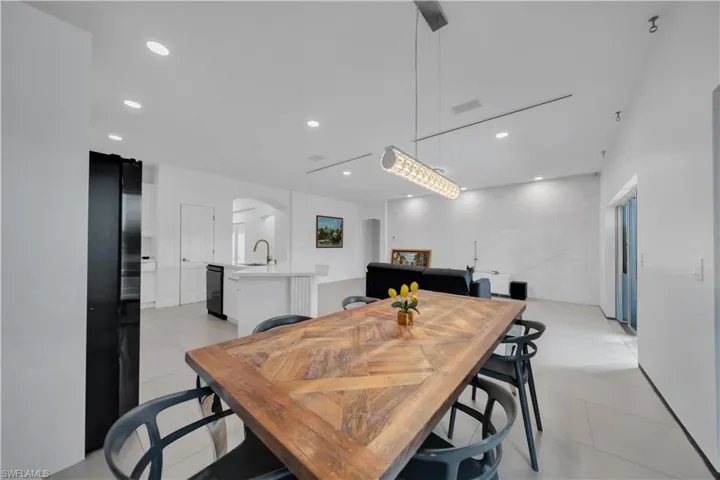 Dining room with arched walkways, recessed lighting, and light tile patterned floors