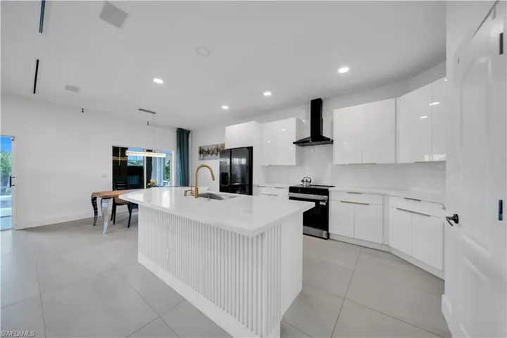 Kitchen with hanging light fixtures, a kitchen island with sink, white cabinets, modern cabinets, and recessed lighting