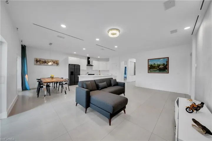 Living area with arched walkways, recessed lighting, and light tile patterned floors