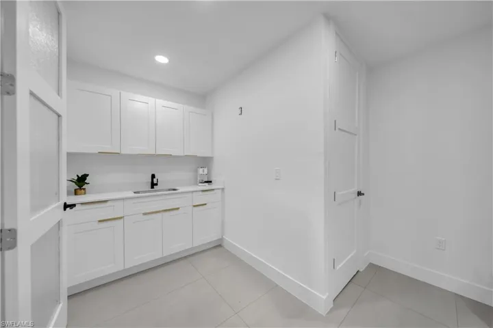 Bar with white cabinetry, light tile patterned floors, and recessed lighting