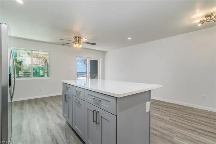 Kitchen with gray cabinets, stainless steel fridge with ice dispenser, ceiling fan, a kitchen island, and recessed lighting