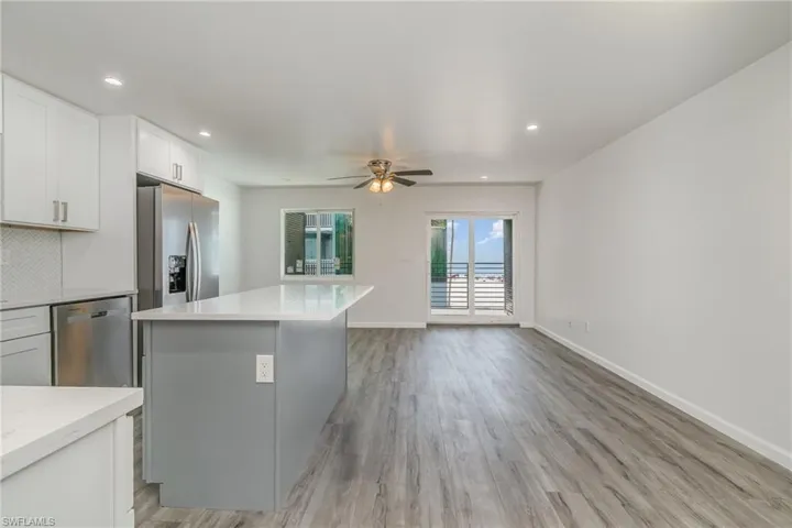 Kitchen with stainless steel appliances, light wood-style flooring, recessed lighting, a center island, and light stone counters