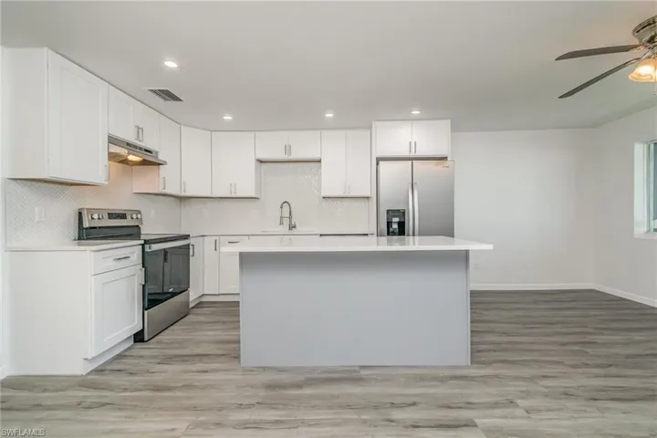 Kitchen featuring stainless steel appliances, white cabinets, a center island, a ceiling fan, and recessed lighting