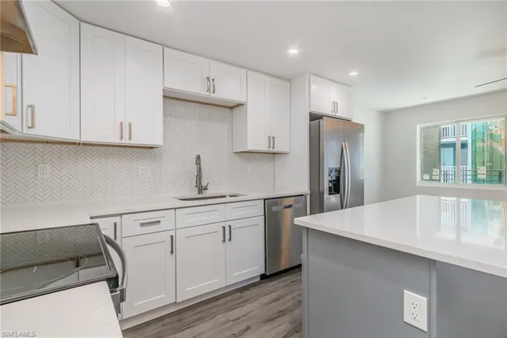 Two tone kitchen featuring stainless steel appliances, light stone countertops, light wood-style flooring, recessed lighting, and backsplash