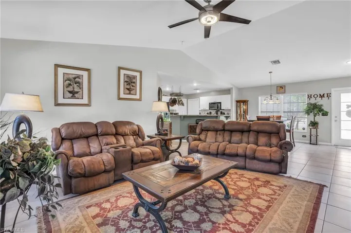 Tiled living room featuring lofted ceiling and ceiling fan