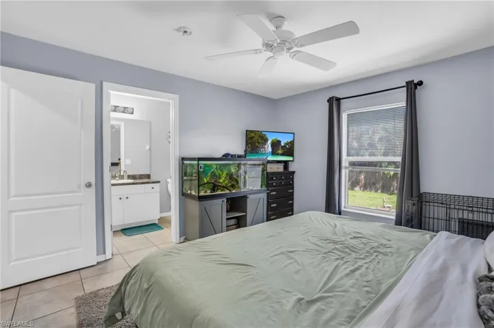 Bedroom with sink, light tile patterned floors, ensuite bath, and ceiling fan