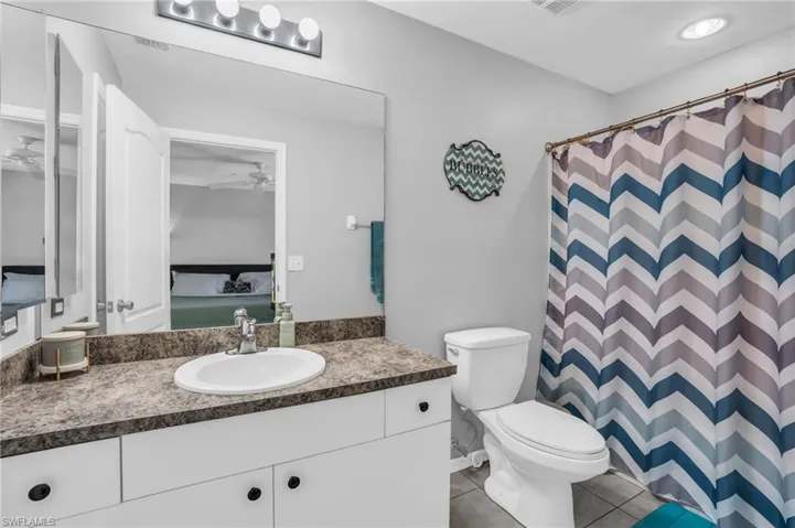 Bathroom featuring vanity, tile patterned flooring, ceiling fan, and toilet