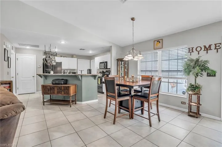 Dining space featuring light tile patterned flooring, an inviting chandelier, and vaulted ceiling