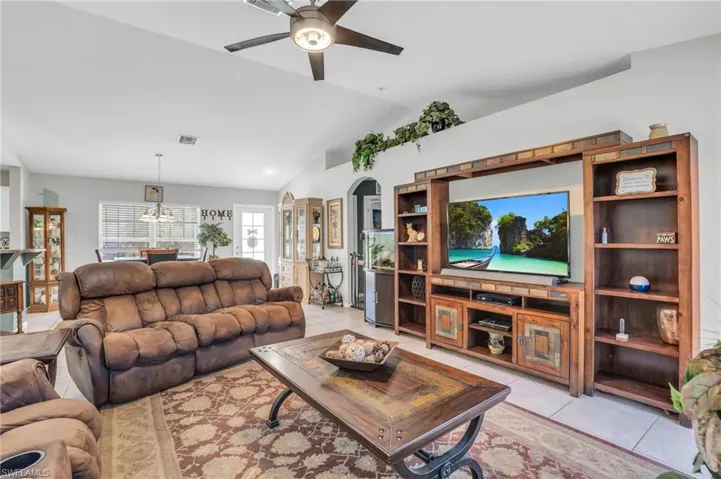Living room featuring ceiling fan, lofted ceiling, and light tile patterned floors