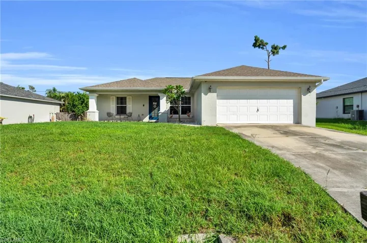 Ranch-style house with a garage, central AC unit, and a front lawn