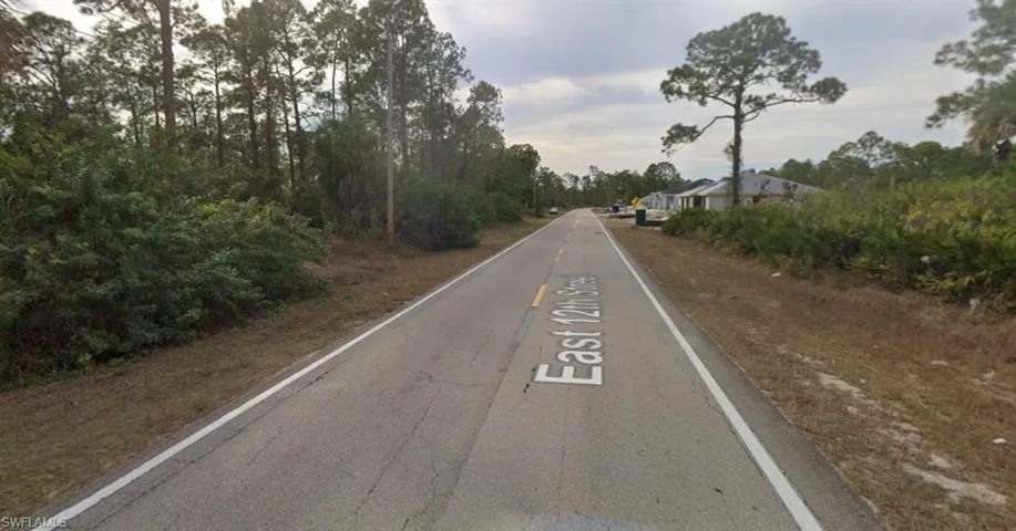 View of asphalt road with view of wooded area