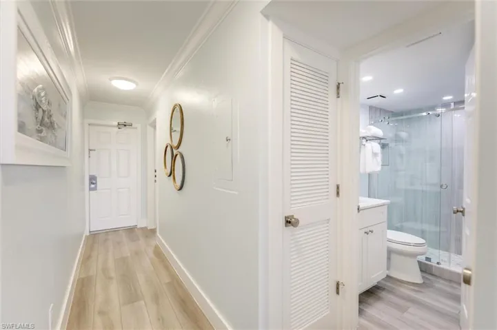 Hallway featuring light wood-style flooring, electric panel, and ornamental molding