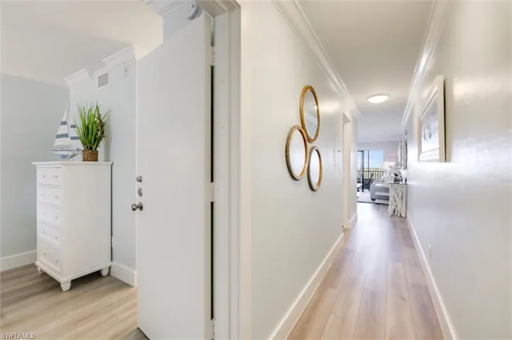 Hallway with ornamental molding and light wood finished floors