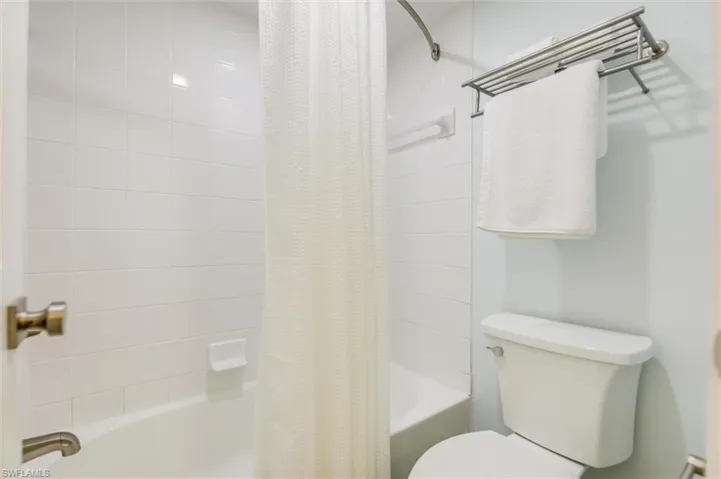 Full bathroom with shower / bath combination with curtain and toilet