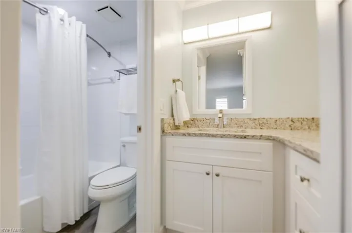 Full bath featuring shower / bath combo with shower curtain, vanity, and dark wood-style floors