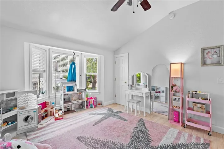 Rec room with lofted ceiling, ceiling fan, and light wood finished floors